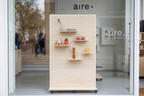 Module Vitrine Aire – présentoir pegboard double face en bouleau avec rangement à casiers sur roulettes en boutique