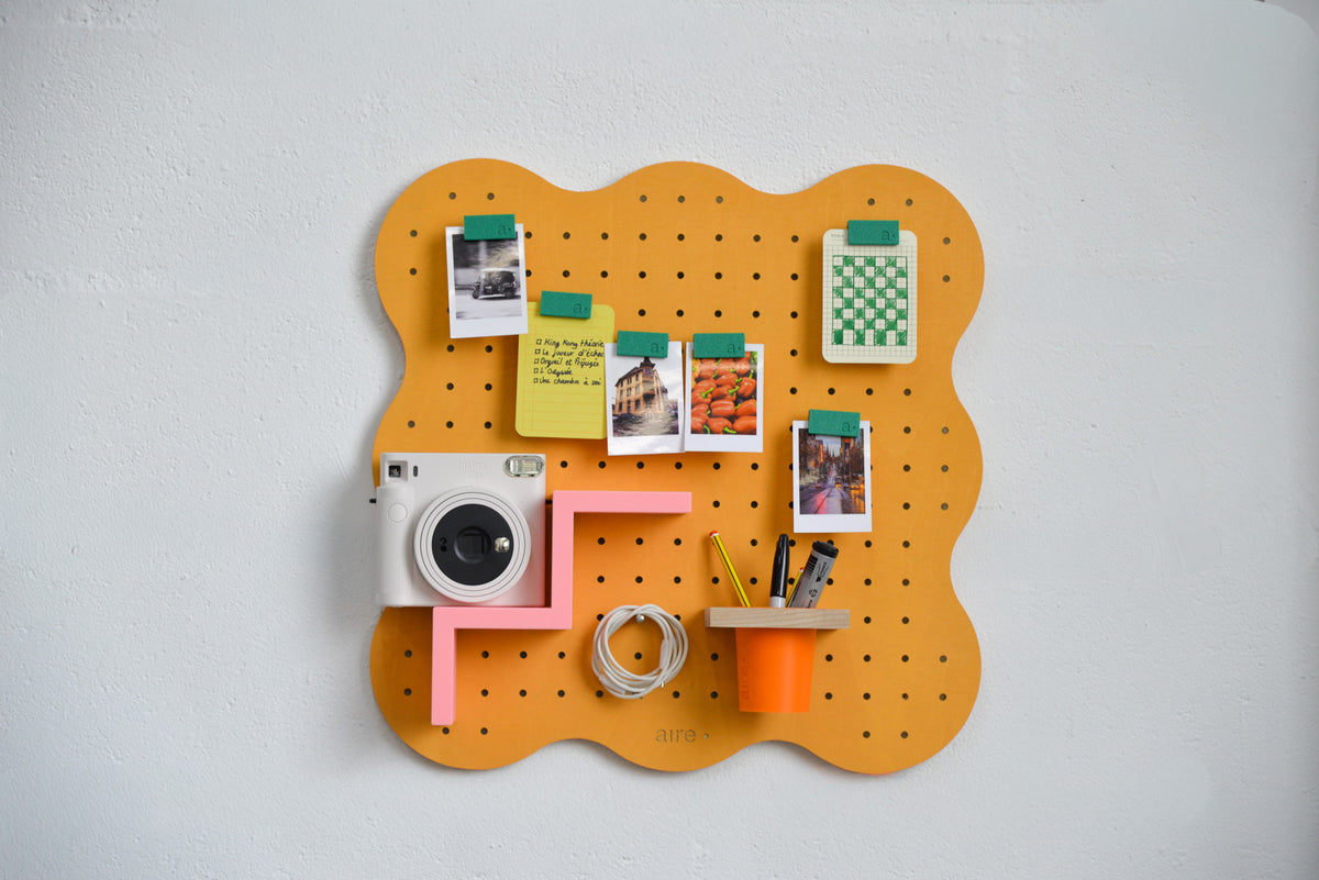 Pegboard Curves orange pastel avec dessins accrochés aux clips magnétiques verts