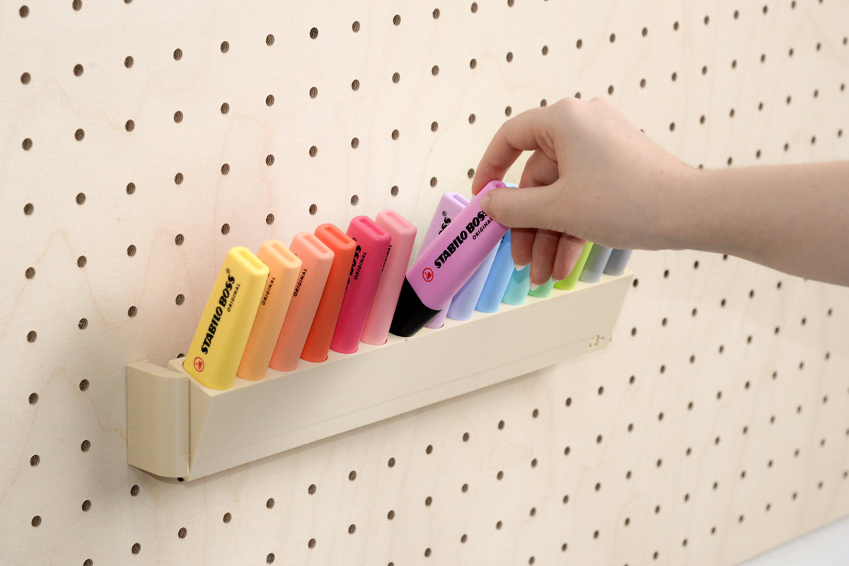 Hand taking a pastel highlighter from the tilting pegboard holder - Aire