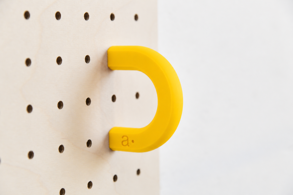 Anneau coloré jaune taille M sur un pegboard en bouleau