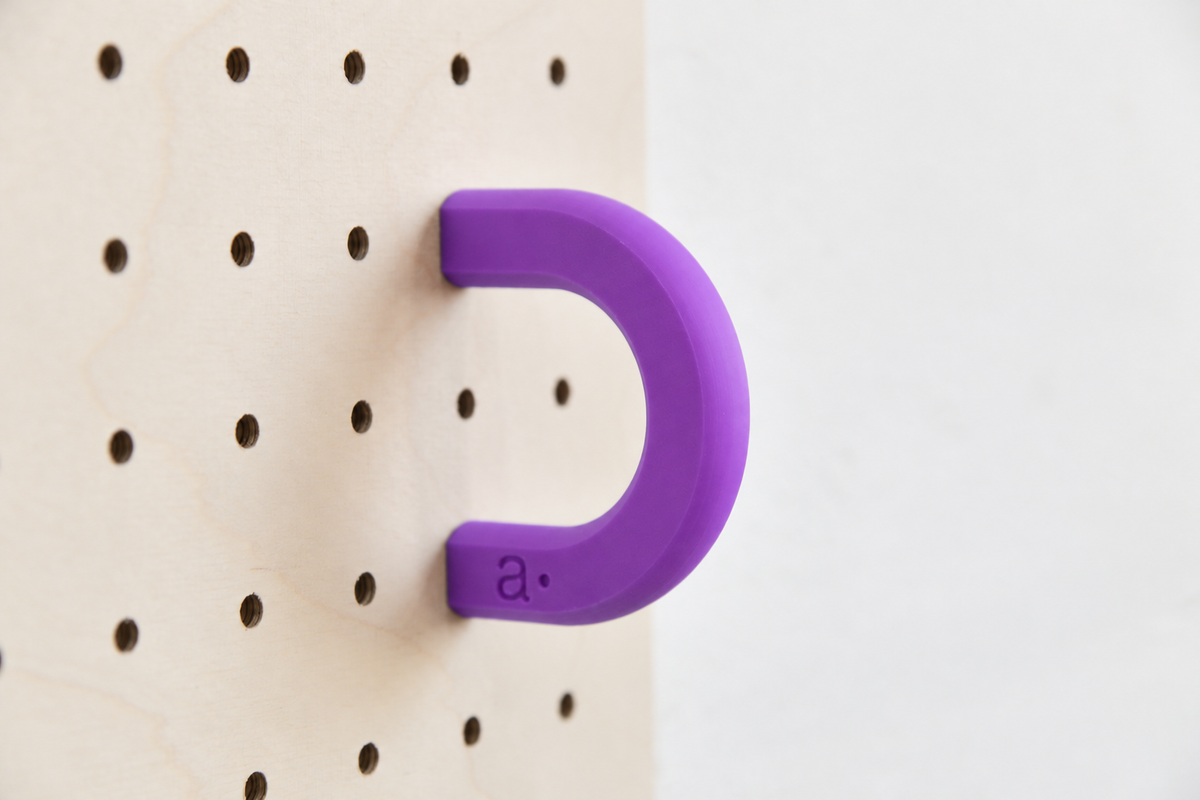Anneau coloré violet taille M sur un pegboard en bouleau