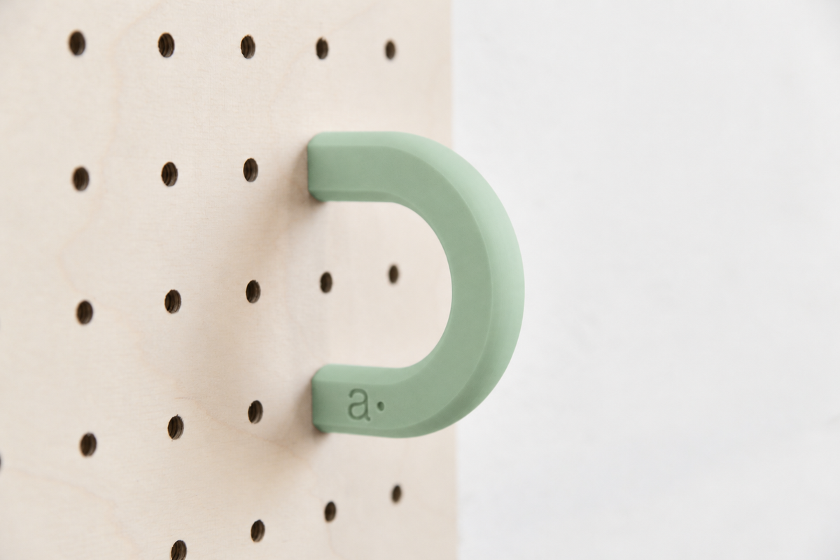Anneau coloré vert sauge taille M sur un pegboard en bouleau