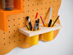 Pot à crayons suspendu double sur pegboard Curves orange pastel, rempli de crayons et feutres