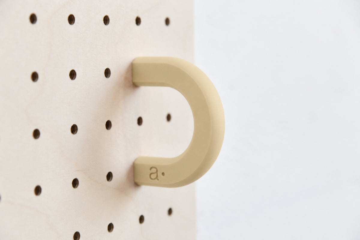 Anneau coloré beige taille M sur un pegboard en bouleau