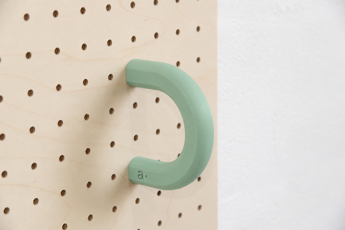Anneau coloré vert sauge taille L sur un pegboard en bouleau
