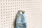 Denim cap hung by its strap on the Aire pegboard cap holder