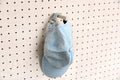 Wall cap holder for pegboard with a blue cap hanging on it
